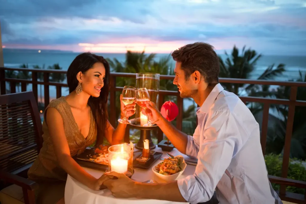 Couple having a romantic dinner on a terrace with a sea view, surrounded by candlelight and an intimate atmosphere.