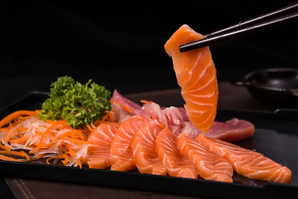 Fresh slices of salmon sashimi served on a plate, ready to be enjoyed as a delicacy.