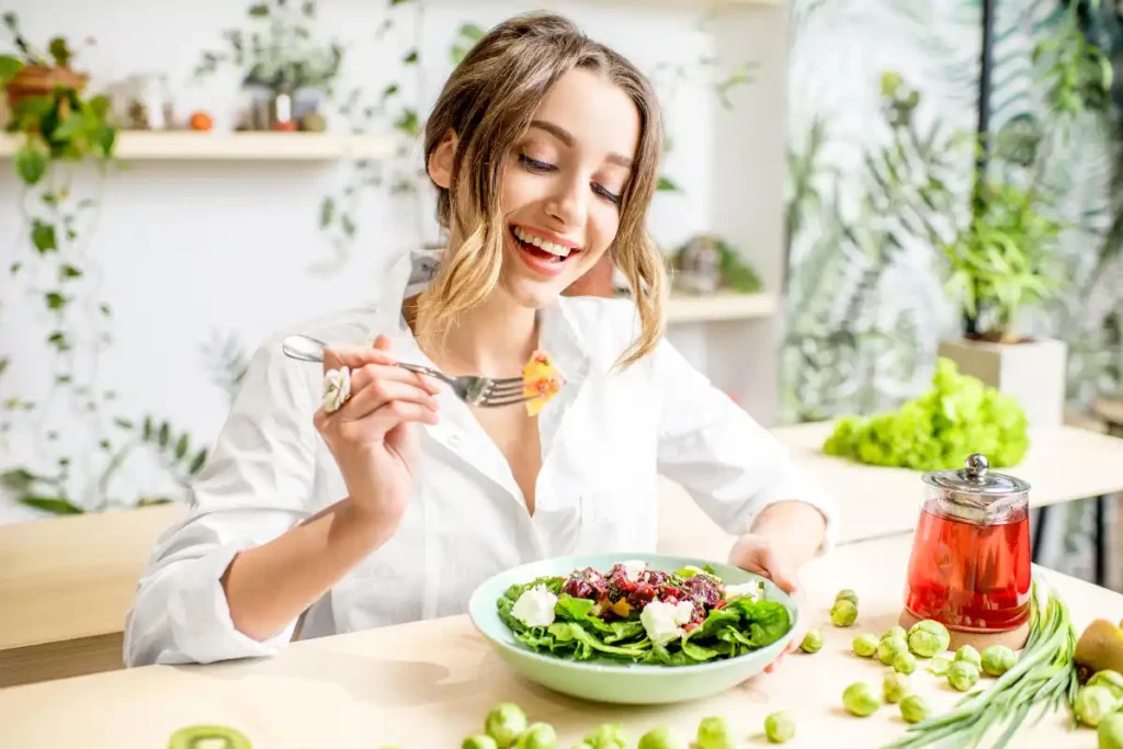 Woman enjoying a plate of healthy green food, including leafy vegetables and fresh greens, promoting a nutritious diet.
