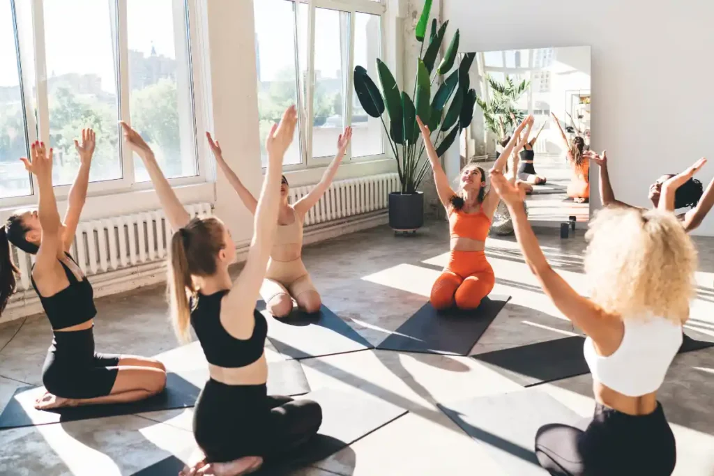 Women sitting in Seiza (Kneeling Pose) during a yoga class, focusing on their practice in a calm environment.