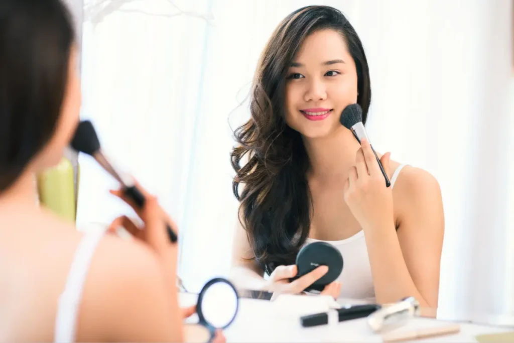A beautiful woman applying makeup in front of a dressing table, carefully enhancing her features with a mirror and makeup tools.