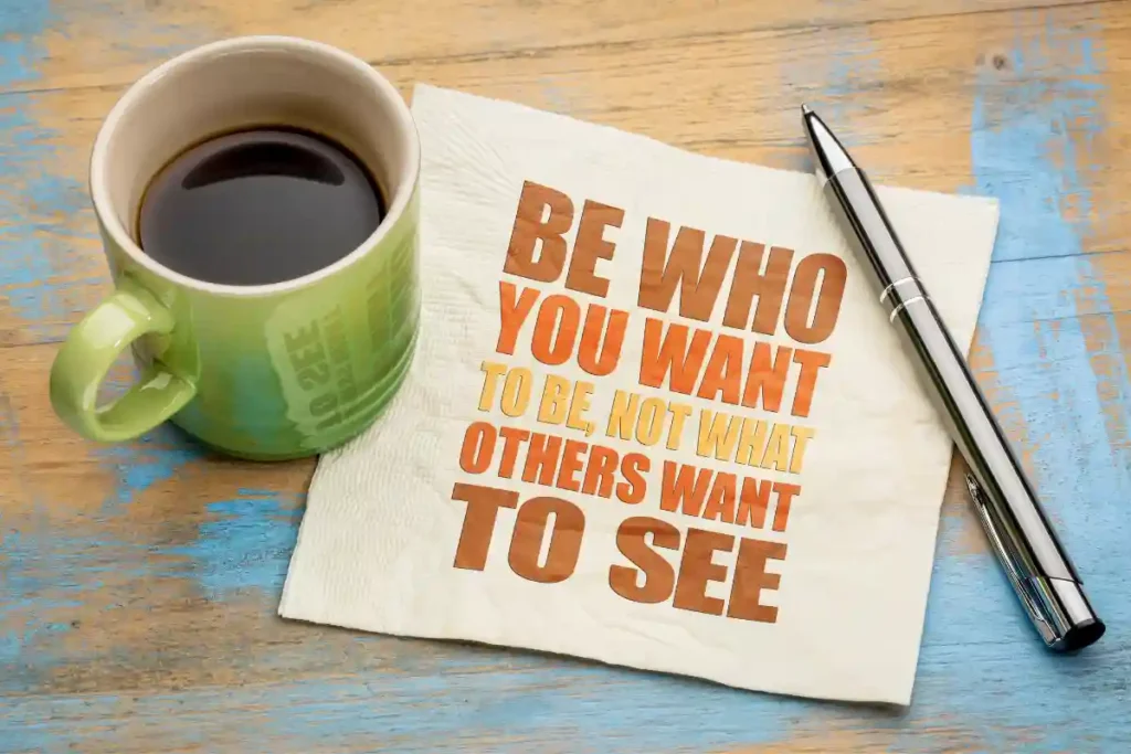 Coffee cup on a table with a napkin featuring the text 'Be who you want to be, not what others want to see'.