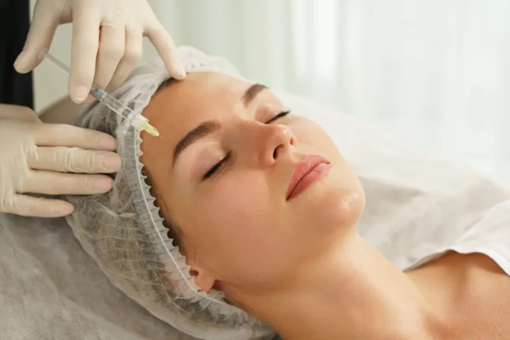 Dermatologist administering a Botox injection to a woman's forehead in a professional skincare treatment setting.