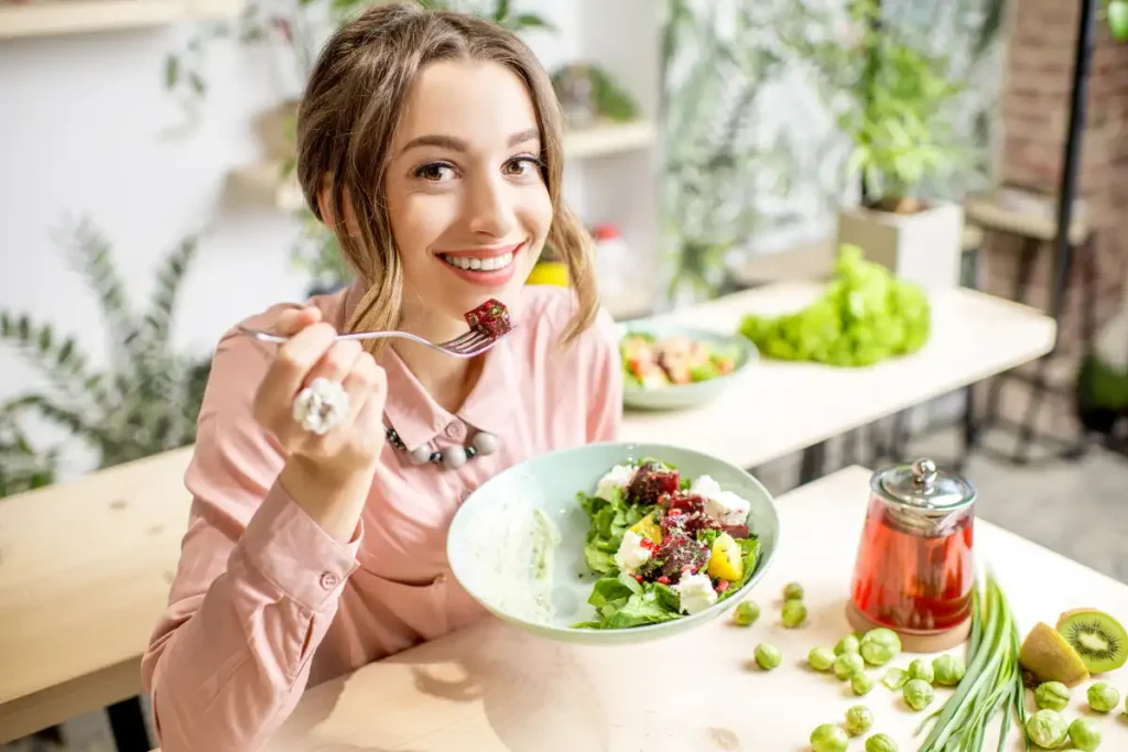 A woman enjoying a plate of healthy green food, including vegetables and leafy greens, as part of a balanced diet.
