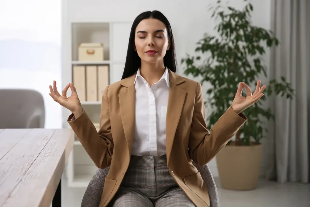 Woman sitting in an office chair, practicing meditation in a peaceful setting.