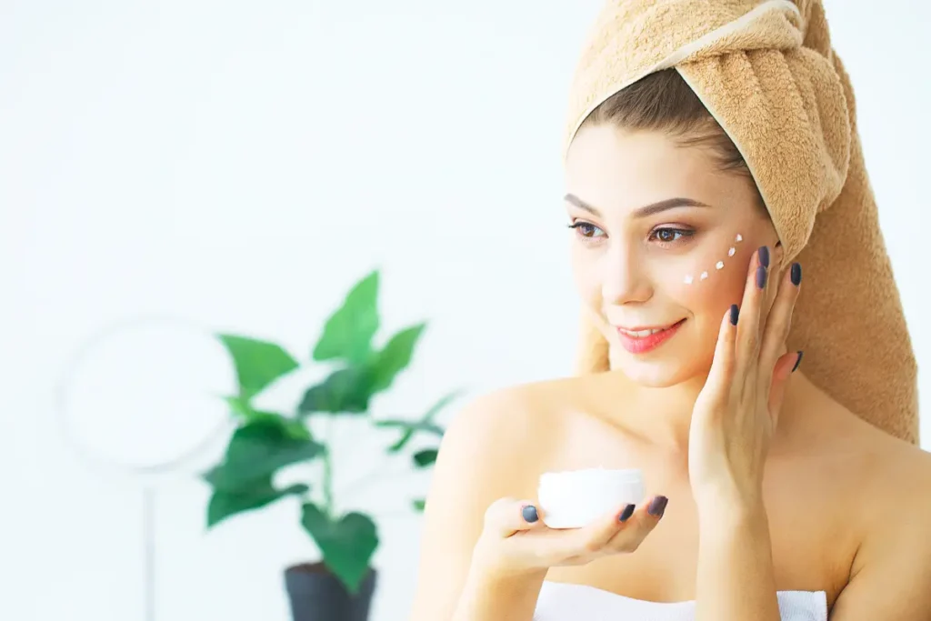 A woman gently applying cosmetic cream to her face as part of her skincare routine, focusing on hydration and nourishment.