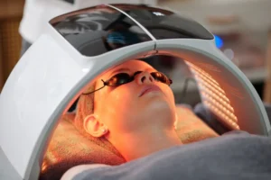 Woman undergoing facial beauty treatment with red LED light therapy.