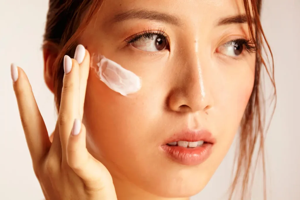 Woman applying niacinamide-based serum to her face, promoting skin hydration and reducing redness.