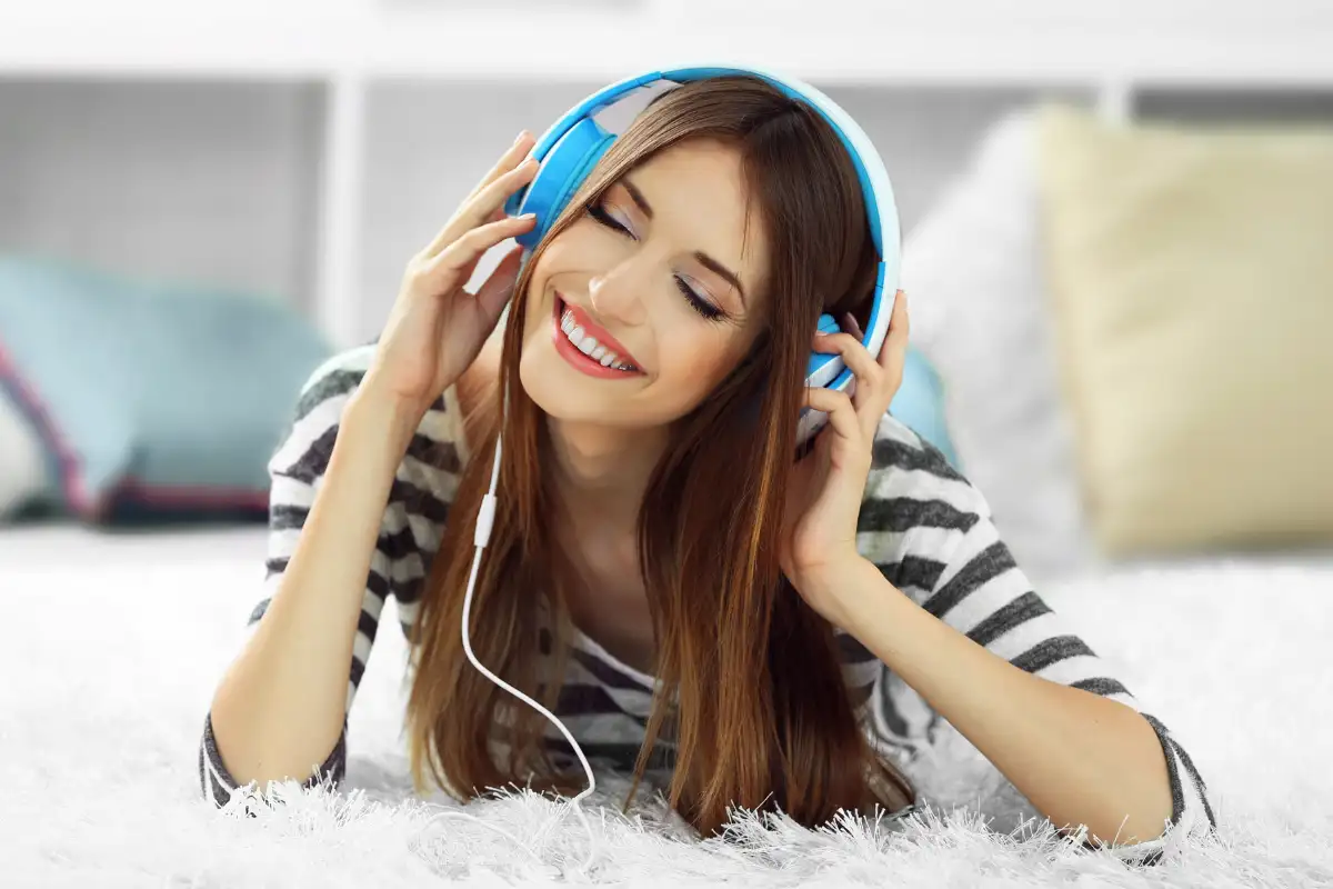 Woman lying in bed, listening to music through headphones, enjoying a moment of relaxation.