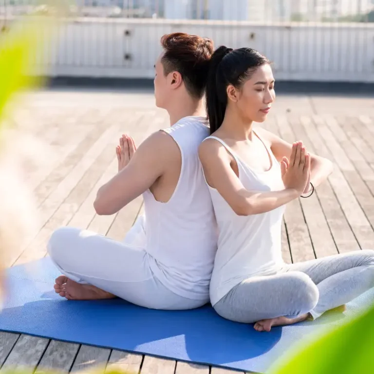 Couple practicing yoga on a rooftop of a building in the city, enjoying a peaceful moment with a skyline view.